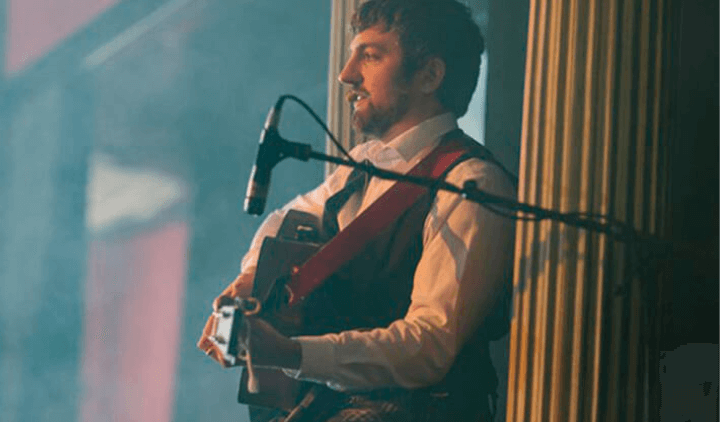 Músico cantando y tocando la guitarra durante un espectáculo típico escocés
