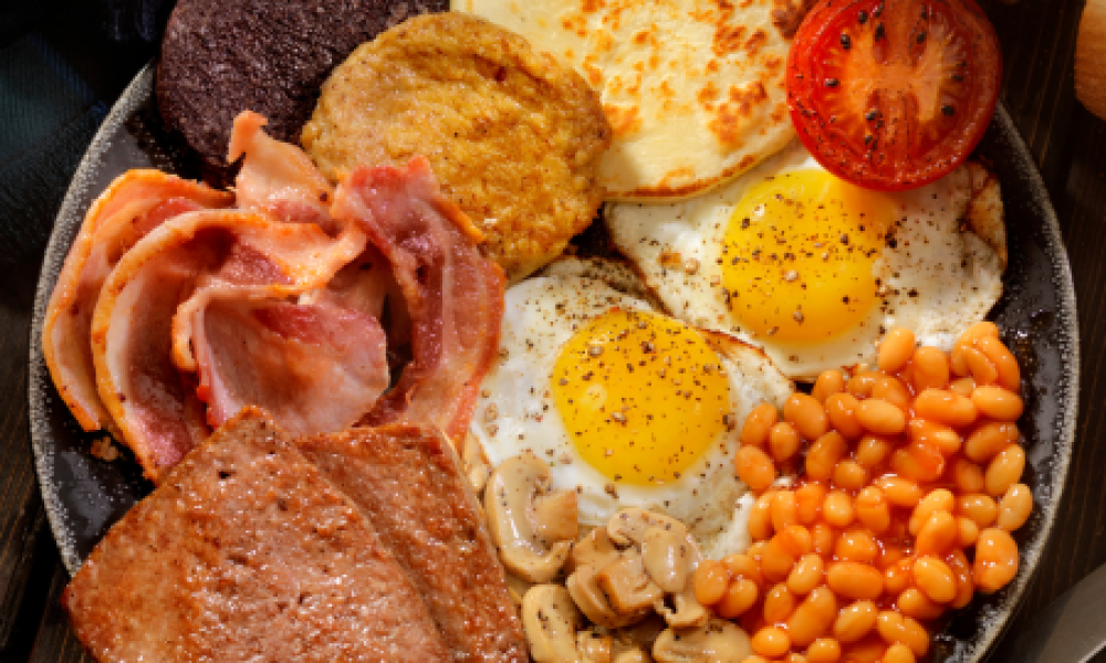 Desayuno tradicional escocés con haggis, pudding, salchichas, bacon, alubias, champiñones, tostada y tomate